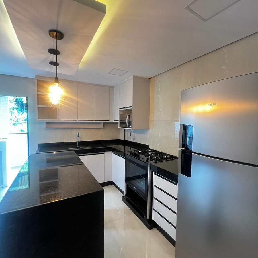 Cozinha com bancada em granito preto e pendente aceso, projeto da U.P.FÉ